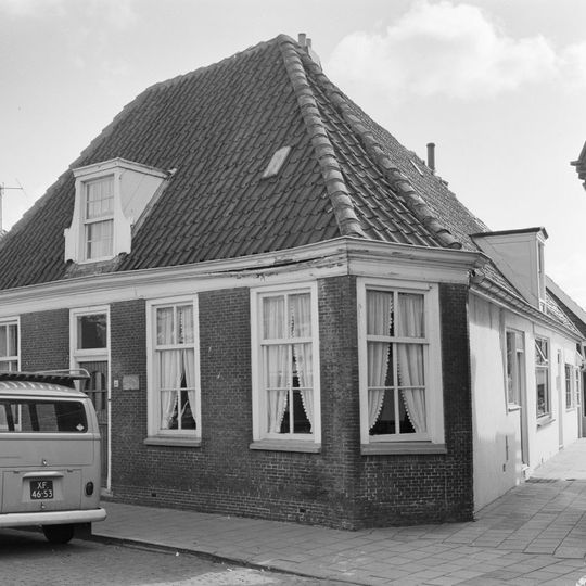 Pand onder verdieping, onder hoog pannen schilddak. Vensters met zesruitsschuiframen en houten kroonlijst
