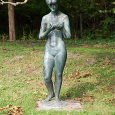 Stehende Frau, aus Metall, auf Betonsockel