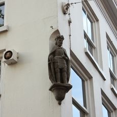 Pand met gepleisterde lijstgevel, op de hoek een beeld geplaatst