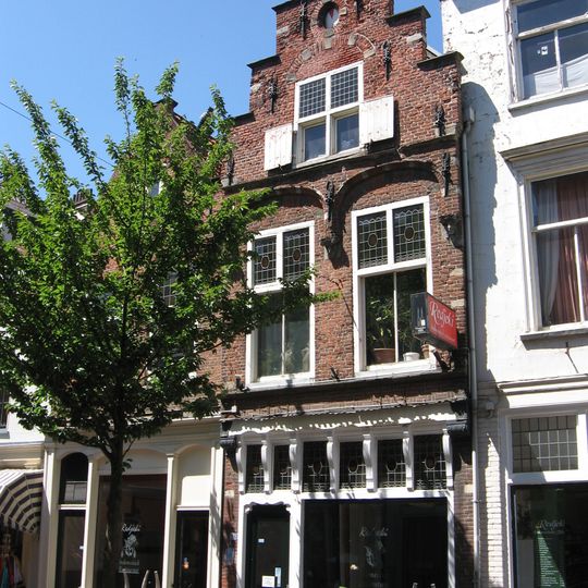 Pand met rijke trapgevel, waarvan de verdiepingen boven de vensters geprofileerde geblokte ontlastingsbogen op Jonische kapitelen met gebeeldhouwde koppen heeft