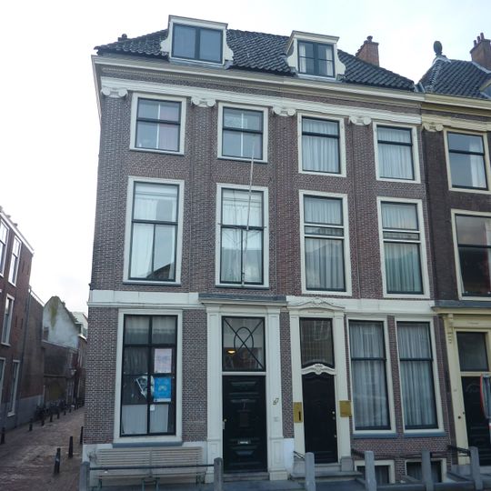 Pand onder een dak met het nr 57. Ionische pilasterstelling over beide verdiepingen. Hardstenen stoep met palen