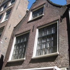 Huis met gevel onder klokvormige top met rollagen