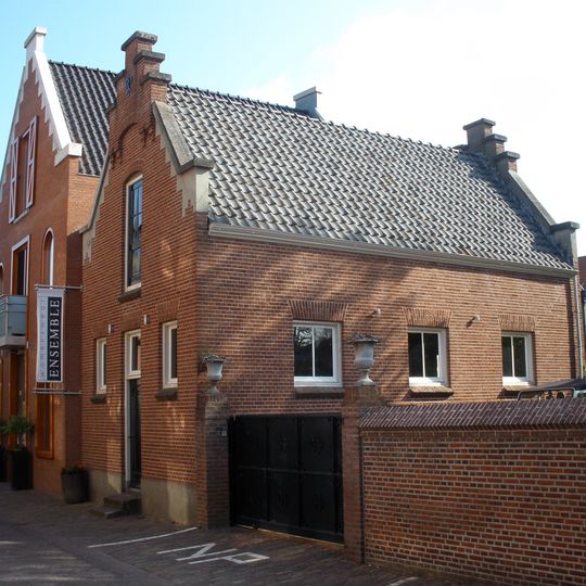 In rode baksteen over één bouwlaag opgetrokken werkplaats op een rechthoekige plattegrond onder een zadeldak met Hollandse pannen