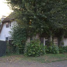 Boerderij uit de 18e eeuw met rieten wolfdak, gepleisterde voorgevel, waarin twee vensters met luiken en 16-ruitsschuiframen en vlechtingen in de zijgevels