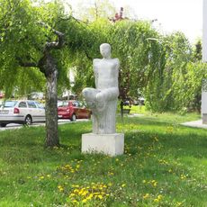 Kamenná plastika sedící ženy v Smetanově ulici v Novém Městě na Moravě