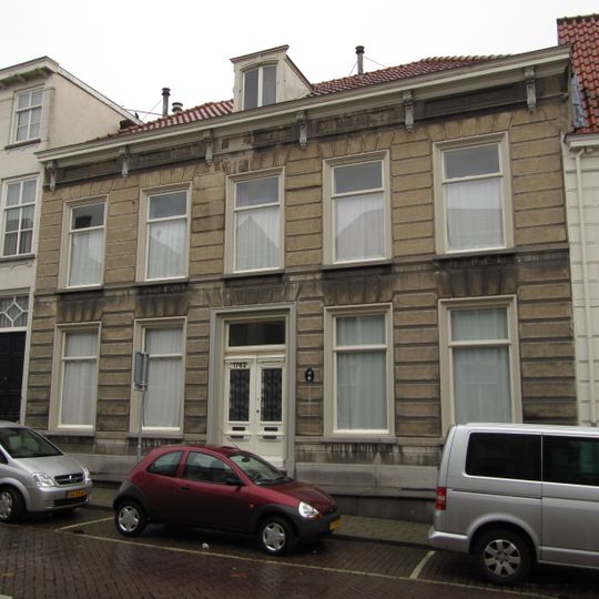 Huis met gebosseerd grijsgepleisterde lijstgevel, kroonlijst op consoles