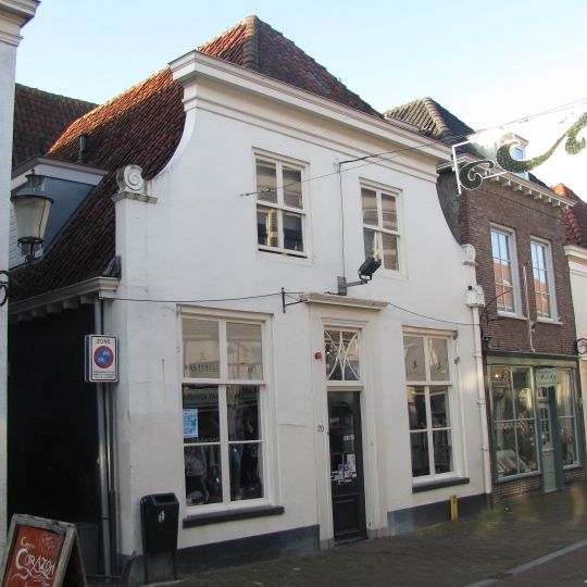 Huis met door rechte kroonlijst afgeknotte gepleisterde gevel, aan de achterzijde trapgevel