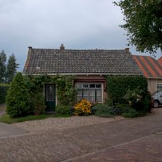 Hoeve op L-vormige plattegrond onder pannen daken. Daklijst met consoles