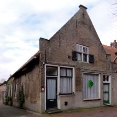 Pand met IJsselstenen puntgevel, voorzien van vlechtingen en geprofileerde dekplaten opzij en op de top. Kruiskozijnen en luiken (onderdeel van buurnummer 14)