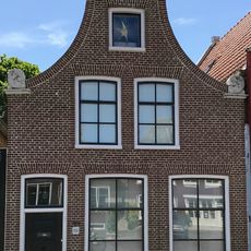 Pandje onder zadeldak tegen klokgevel met aanzetkrullen