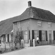 Boerderij op T-vormige plattegrond, waarvan het gepleisterde woongedeelte een verdieping en een dwars rieten schilddak draagt