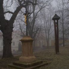 Boží muka a dřevěná zvonička na návsi před kostelem sv. Petra a Pavla v Peruci