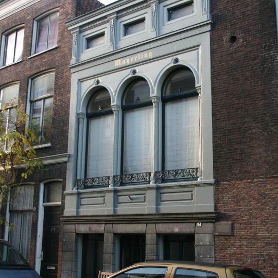 Pand met rijk versierde lijstgevel met rondboogvensters, voorzien van geschroefde railtjes