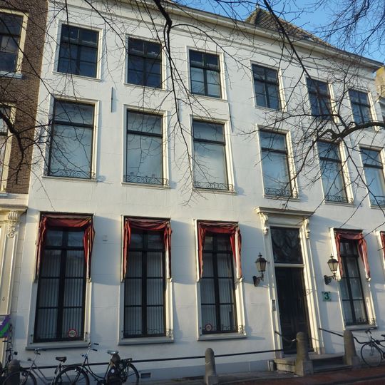 Pand met gepleisterde dubbele bakstenen gevel met rechte kroonlijst. Gesneden dubbele voordeur met bovenlicht. Stoepstangen over hardstenen palen