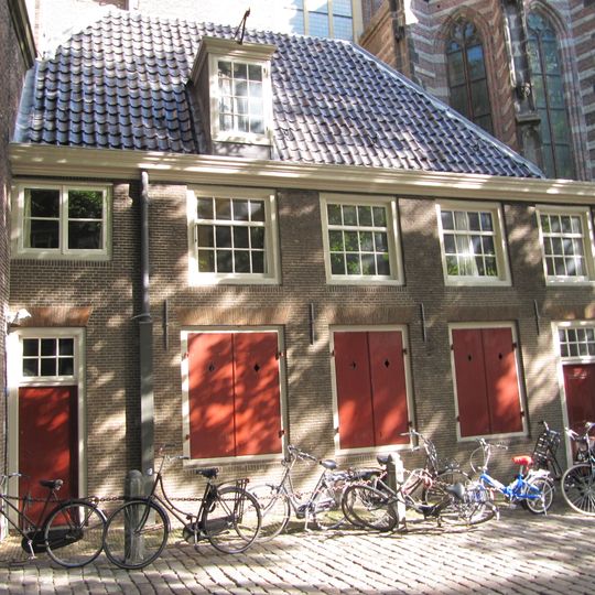 Tegen de zuidzijde van de Oudekerkstoren gebouwd huis, ten dele onder schilddak, ten dele onder plat dak