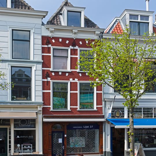 Pand onder schilddak en met in de gevel natuurstenen banden en geblokte ontlastingsbogen. Sierankers. Kroonlijst met verdiepte panelen en drie gesneden Lod. XIV consoles