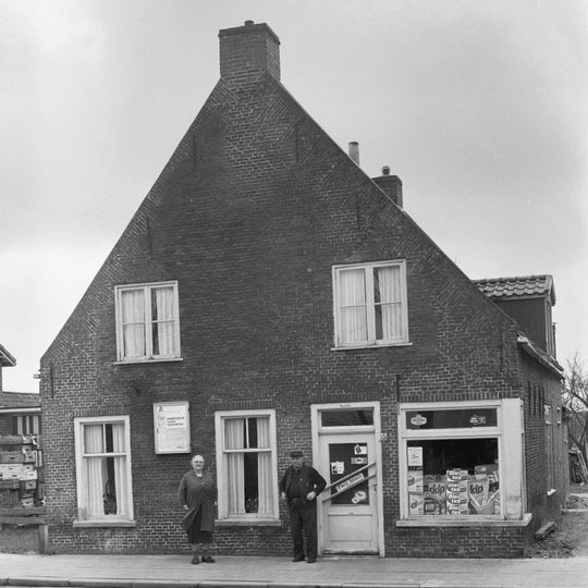Woning onder zadeldak tegen forse topgevel met vlechtingen in het metselwerk en op de zolderverdieping twee vierruitsvensters