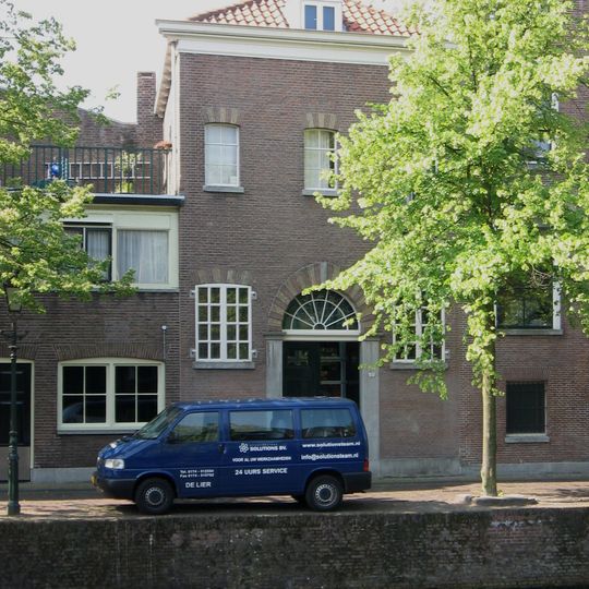 Pakhuis met lijstgevel. Getoogde poort op hardstenen pilasters met hoofdgestellen. In rode en gele steen geblokte poortboog
