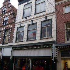 Pand met brede trapgevel in haarlemse trant met natuurstenen blokken in bogen boven ramen en horizontale banden