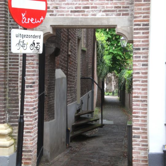 Bakstenen poortje met klokgevelvormige bekroning, gedekt met natuursteen