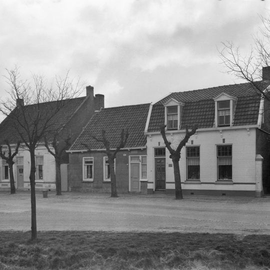 Eenvoudig dorpshuis, nok evenwijdig aan de rooilijn, gepleisterde gevel