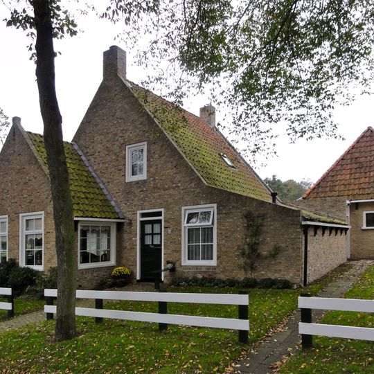 Pandje met zesruitsvensters onder zadeldak tegen topgevel met beitelingen en topvenster terzijde van het rookkanaal