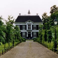 Landhuis met hoog leiendak, fronton op de middentravee, dakruiter, geblokt grijsgepleisterde gevel
