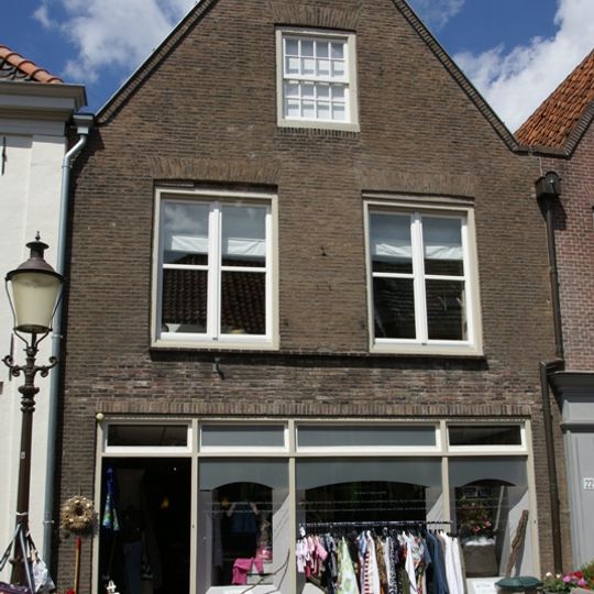 Gebouw onder dwars schilddak en met deels gebosseerde, deels gladgepleisterde lijstgevel, met middenrisaliet, cordonlijst, ingangen met rondbogen, daarboven zesdelige schuiframen