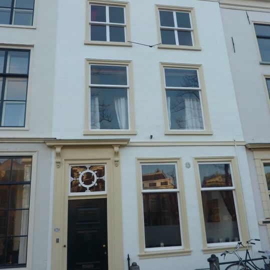 Pand met gepleisterde gevel met rechte kroonlijst. Stoep en stoeppalen