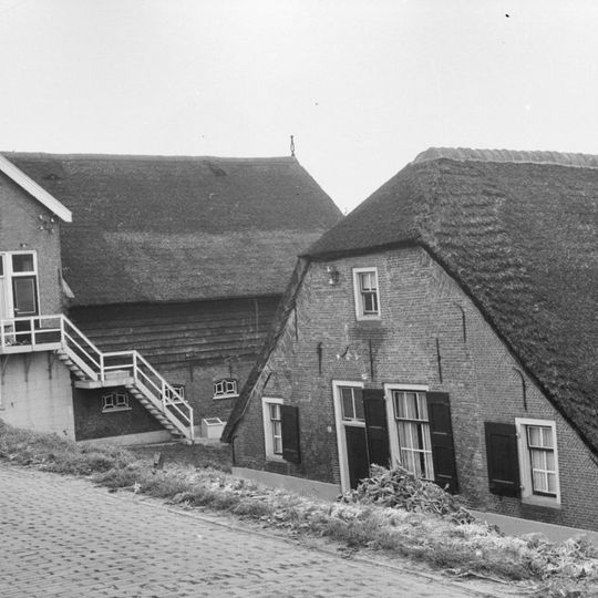 Boerderij onder rieten zadeldak. Voorgevel met vlechtingen en geblokte ontlastingsboog
