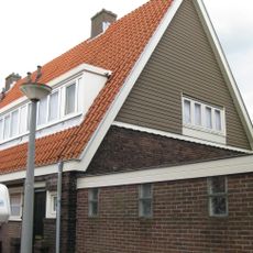 Blok met 8 keukenwoningen, zo genoemd vanwege destijds nieuwe plaatsing van keuken aan de voorzijde, aan de zijkant een houten topgevel, bouwstijl Amsterdamse School.