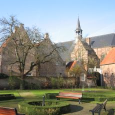 Diep achter een poort gelegen groot huis onder dwars zadeldak tussen zijtrapgevels