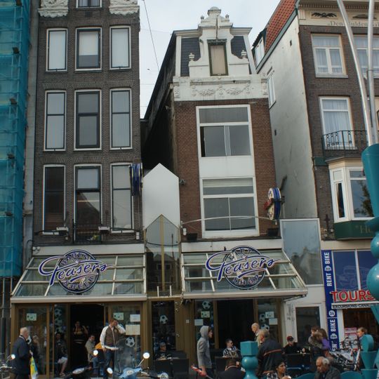 Pand met halsgevel met rijk gebeeldhouwde gedeelde vleugelstukken en gelobde volutenafdekking waarin ornament