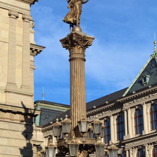 Sloup se sochou Genia vpravo od hlavního vchodu Rudolfina v Praze