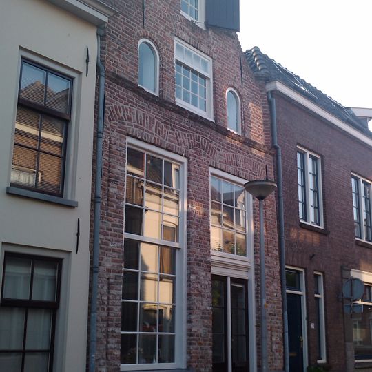 Huis met gepleisterde in- en uitgezwenkte topgevel met vijf overhoekse pinakels