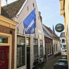 Pand onder zadeldak tegen puntgevel met beitelingen en rond topvenster