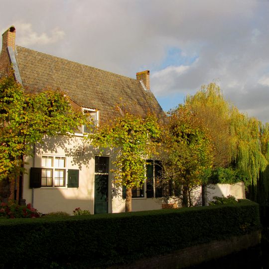 Eenvoudige gepleisterde lage woning met zadeldak, de korte zijden in topgevels eindigend. Terzijde uitgebouwde schoorsteen