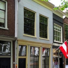 Pand met gepleisterde lijstgevel voor huis met schilddak. Empire schuiframen in de verdieping