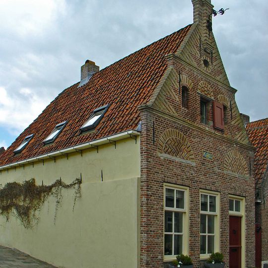 Huis met bakstenen puntgevel met waterlijsten en uitgekraagde toppilaster met sieranker