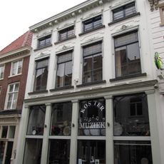 Huis met witgepleisterde en van stucversiering voorziene lijstgevel