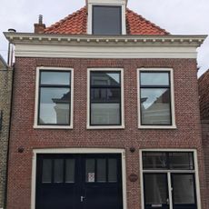 Pand onder schilddak met rechte kroonlijst en topschoorsteen met bord