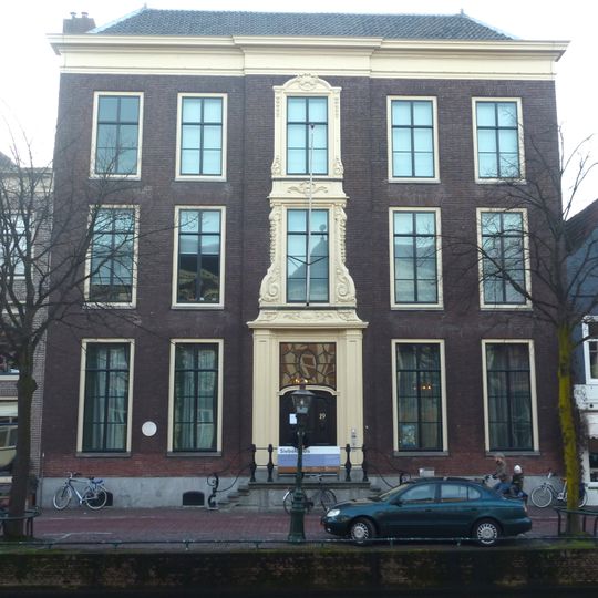 Pand met brede bakstenen gevel. Statig patriciershuis, rechte kroonlijst, gebeeldhouwde houten middenpartij in régence vorm. Hardstenen bordestrap met gesmeed ijzeren leuning