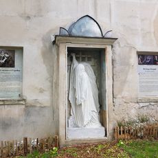 Copie d'une sculpture représentant Henriette-Adélaïde Raspail, épouse de François-Vincent Raspail, enveloppée de son linceul. L'œuvre originale, d'Antoine Étex, se trouve sur la tombe de Raspail au cimetière du Père-Lachaise.