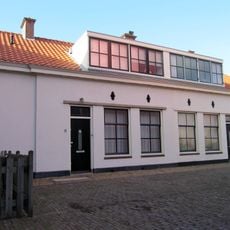 Ten dele gepleisterd pand zonder verdieping, onder met pannen gedekt zadeldak tussen puntgevels