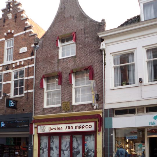 Huis met eenvoudige halsgevel, onder tot winkel verbouwd. Van belang voor nr 45