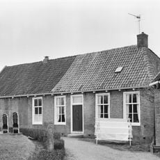 Eenvoudig pand met zesruitsvensters aan de ringweg rond het kerkhof