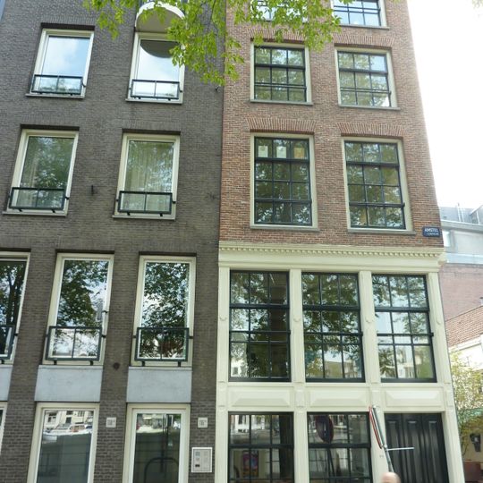 Pand, bestaande uit een hoger opgetrokken voorgedeelte aan de Amstel en een langwerpig achterhuis langs de Bakkerstraat, waarin een eigen toegangsdeur met stoep