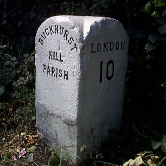 Milestone, by hedge surrounding church